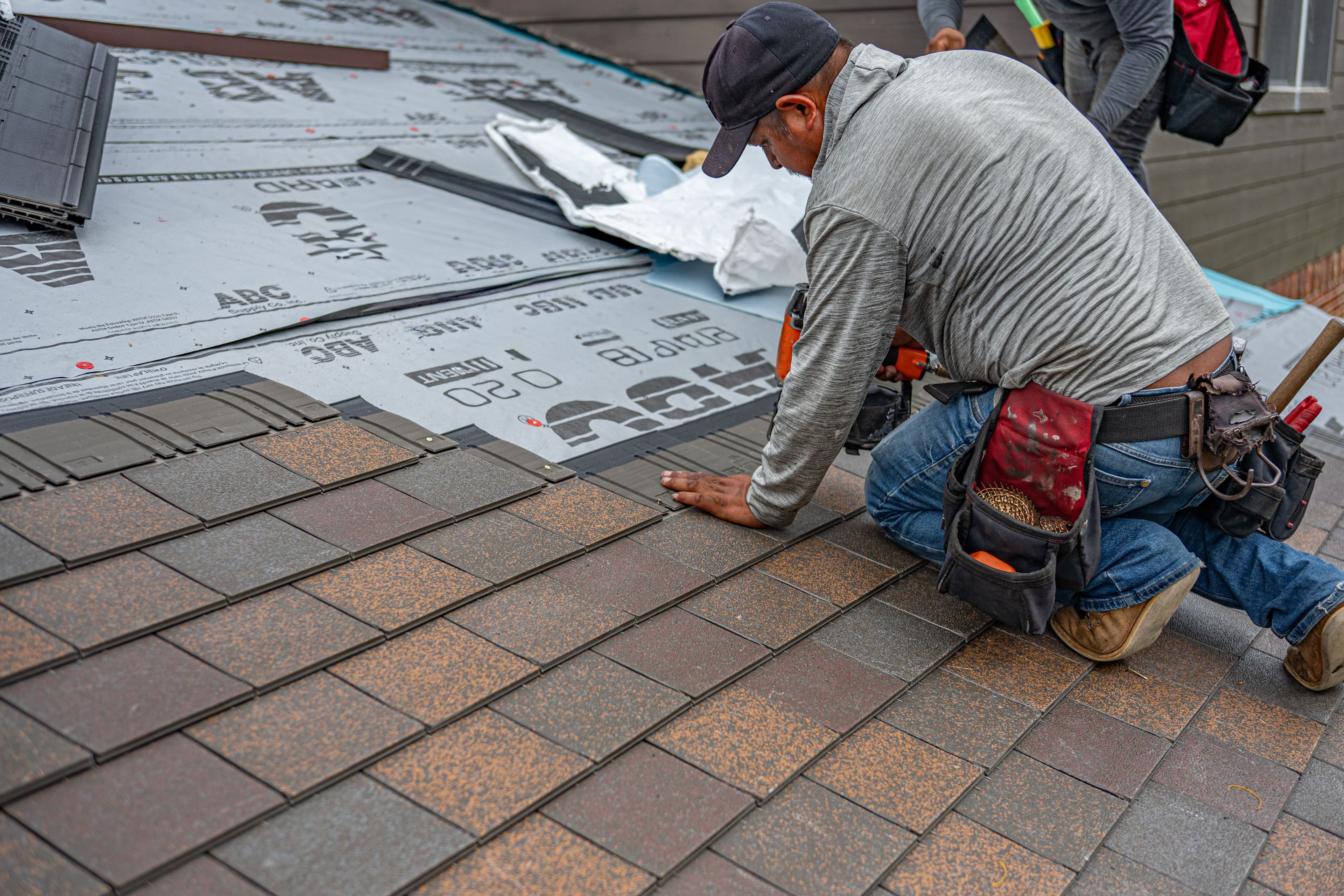 Roofer carefully installing shingles with attention to detail